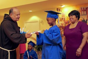 Young student receives his pre-school diploma from Br. Ronald.