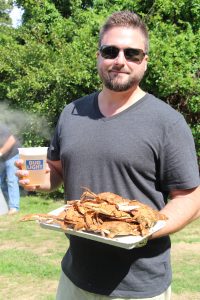 Man in sunglasses holding a beer and a plate of crabs